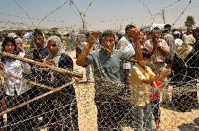 Palestinians wait behind barbed wire at the checkpoint at Rafah